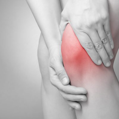 A young woman massaging her painful knee